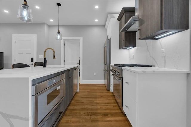 kitchen featuring sink, white cabinetry, hanging light fixtures, a center island with sink, and high quality appliances