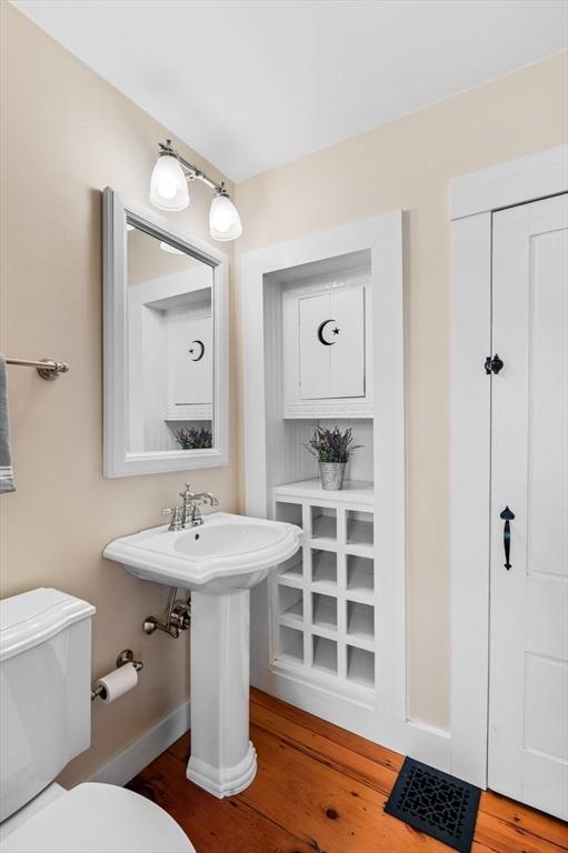 half bath featuring toilet, baseboards, and wood finished floors