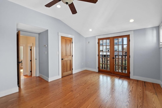 empty room with lofted ceiling, french doors, ceiling fan, light wood finished floors, and baseboards