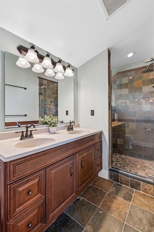 full bath with visible vents, a stall shower, stone finish floor, and a sink