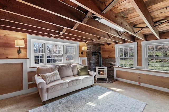 living area with a wood stove, wood ceiling, wood walls, and carpet floors