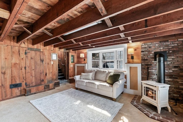 living room featuring a wood stove, beam ceiling, stairway, and wooden walls