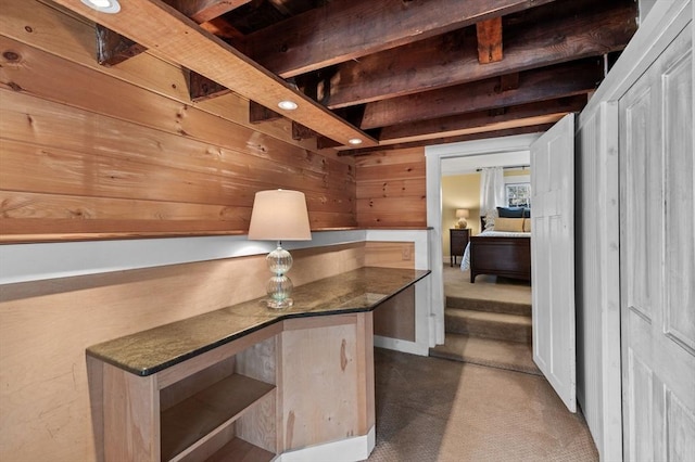 unfurnished office featuring wood walls and carpet flooring