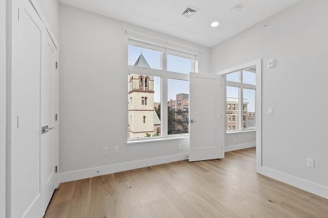 spare room with plenty of natural light, visible vents, baseboards, and wood finished floors