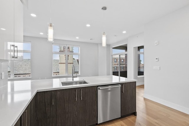 kitchen with dark brown cabinets, dishwasher, light countertops, and a sink