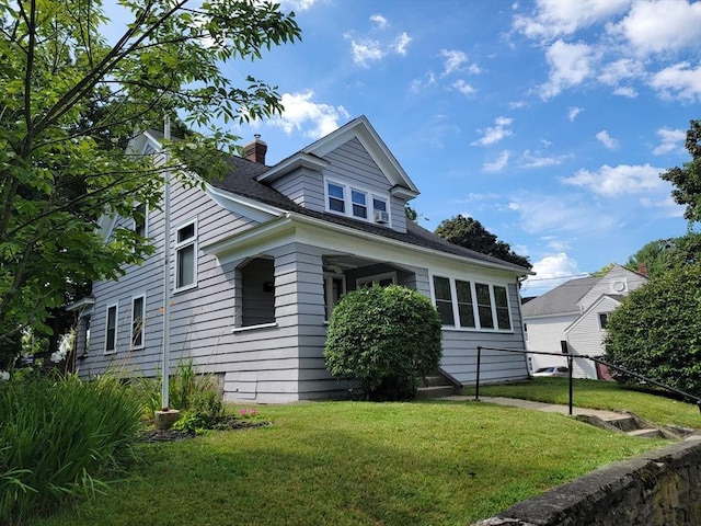 view of front facade with a chimney, a shingled roof, a front lawn, and fence