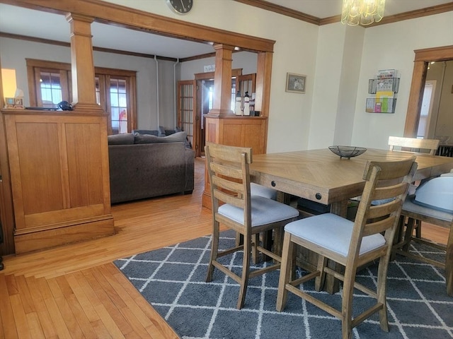 dining area featuring crown molding, decorative columns, and light wood-style floors