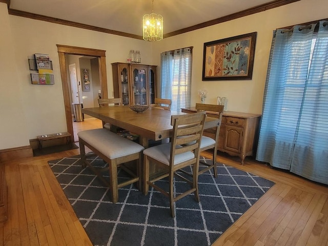 dining space featuring an inviting chandelier, hardwood / wood-style flooring, baseboards, and ornamental molding