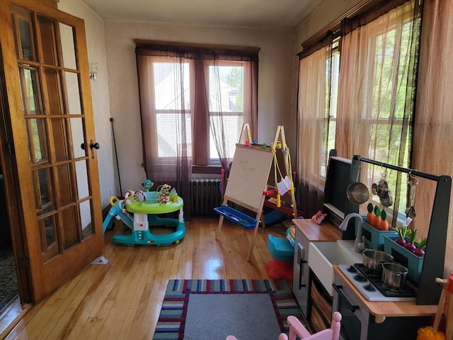 game room featuring radiator and hardwood / wood-style floors