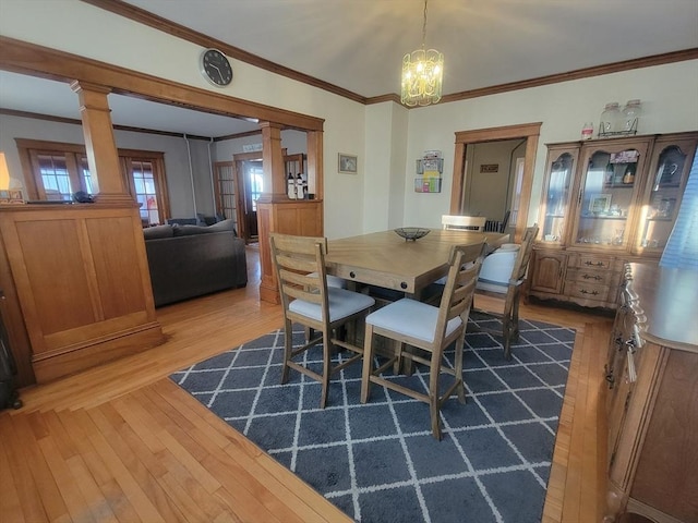 dining area with hardwood / wood-style floors, an inviting chandelier, decorative columns, and ornamental molding