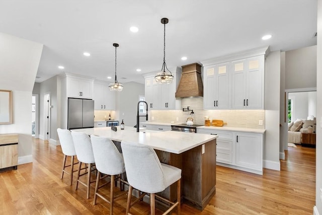 28 Marlboro Rd, Woburn, MA 01801 - kitchen with premium range hood, appliances with stainless steel finishes, backsplash, a kitchen island with sink, and white cabinetry