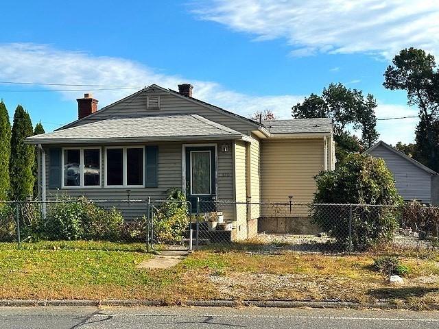 bungalow-style house featuring a fenced front yard, a chimney, and roof with shingles