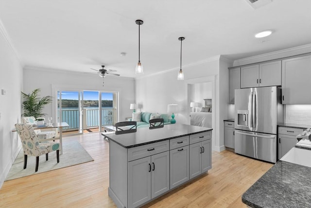 kitchen featuring stainless steel refrigerator with ice dispenser, hanging light fixtures, ceiling fan, gray cabinets, and a kitchen island