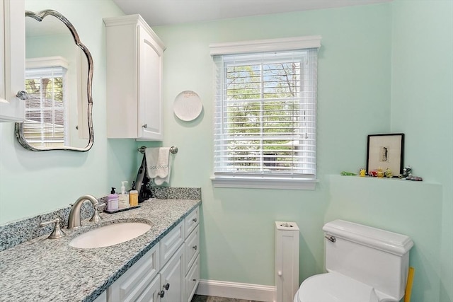 bathroom with toilet, plenty of natural light, and vanity