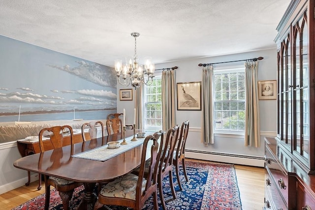 dining space with baseboard heating, a chandelier, light wood-style floors, and a textured ceiling