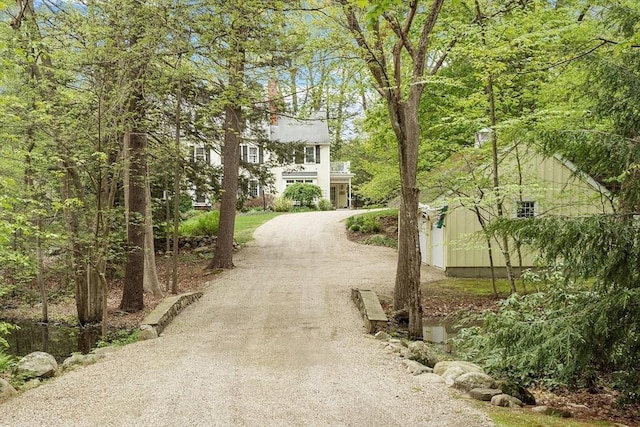 view of home's community featuring driveway and an outdoor structure