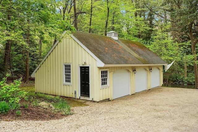 detached garage featuring a view of trees