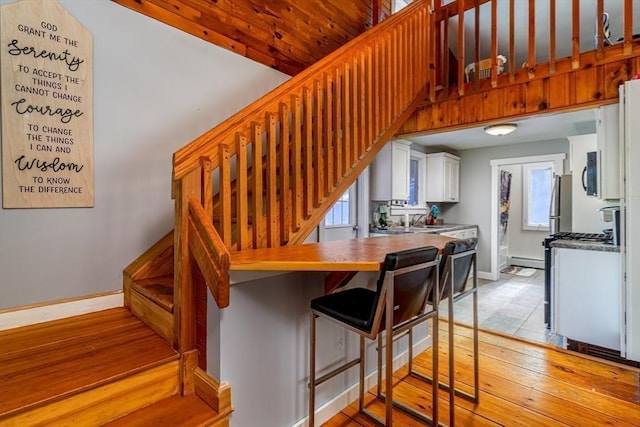 staircase with sink, a baseboard radiator, and hardwood / wood-style floors