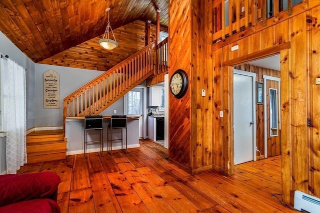 living room with wood-type flooring, a baseboard heating unit, high vaulted ceiling, wooden walls, and wood ceiling