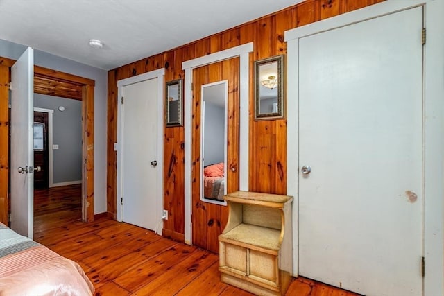 bedroom with light wood-type flooring and wood walls