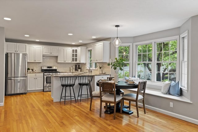 21 Mcdonough Dr, Marlborough, MA 01752 - kitchen featuring stainless steel appliances, light wood-type flooring, white cabinetry, backsplash, and a peninsula