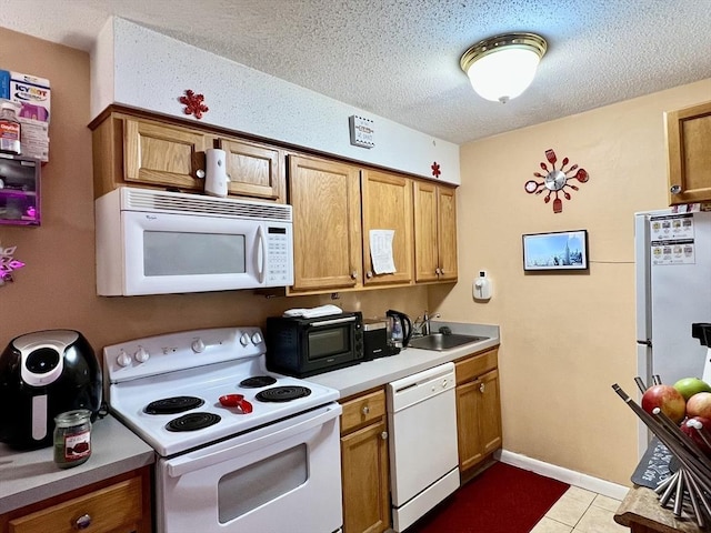 kitchen featuring white appliances, light countertops, a textured ceiling, brown cabinets, and a sink