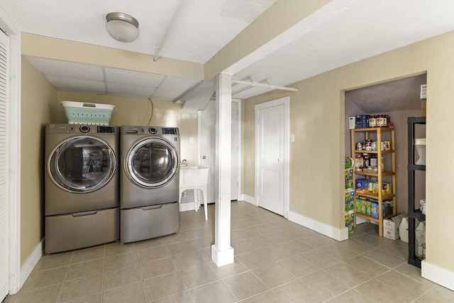 washroom featuring baseboards, laundry area, washing machine and dryer, and tile patterned flooring