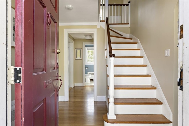 entrance foyer featuring baseboards, ornamental molding, stairs, and wood finished floors