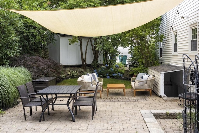 view of patio / terrace featuring a storage unit, outdoor dining space, and an outbuilding