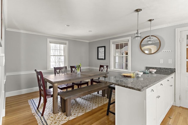 dining room featuring baseboards, ornamental molding, and light wood-type flooring