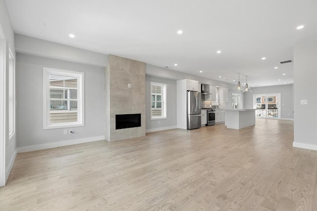 unfurnished living room featuring recessed lighting, visible vents, light wood-style flooring, a large fireplace, and baseboards