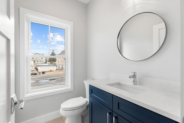 bathroom with toilet, baseboards, wood finished floors, and vanity