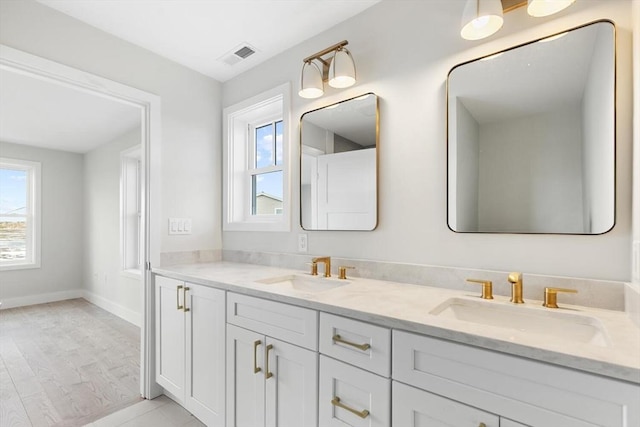 bathroom featuring visible vents, a sink, baseboards, and double vanity