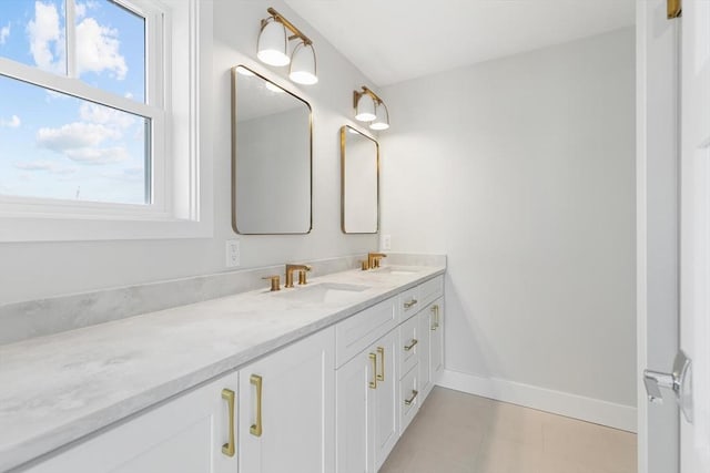 bathroom featuring double vanity, a sink, and baseboards