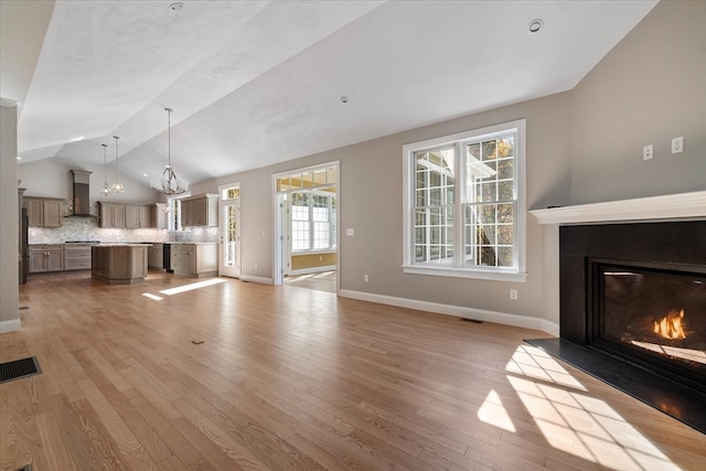 unfurnished living room featuring lofted ceiling and light hardwood / wood-style floors