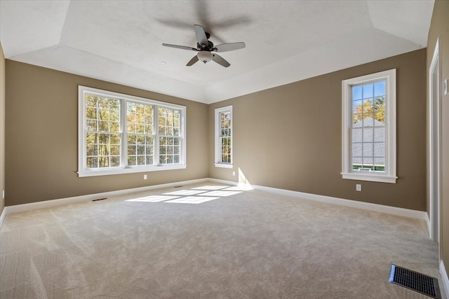 empty room featuring light carpet, lofted ceiling, a raised ceiling, and ceiling fan