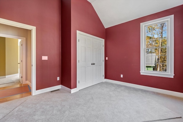 unfurnished bedroom with carpet flooring, a closet, and vaulted ceiling