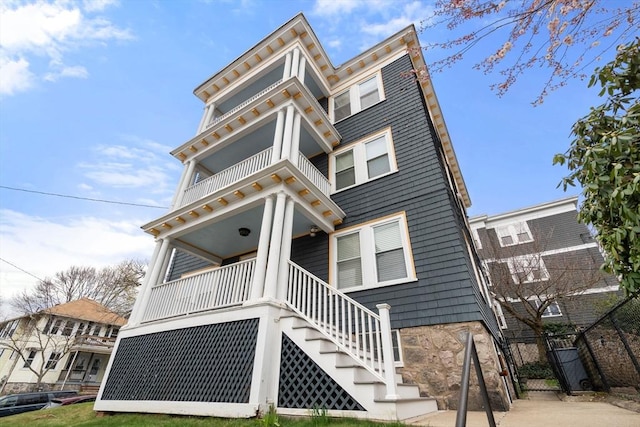 view of front of home with a balcony, stairs, a porch, and fence