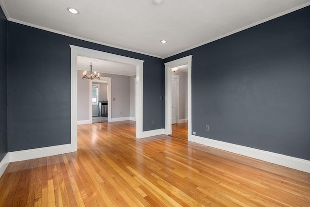 spare room featuring a notable chandelier, crown molding, light wood-type flooring, baseboards, and recessed lighting