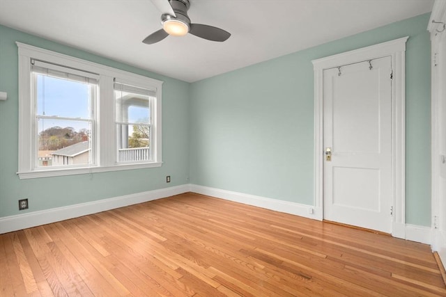 spare room featuring baseboards, light wood-type flooring, and a ceiling fan
