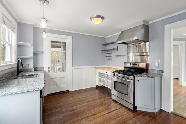 kitchen with a sink, stainless steel gas range oven, open shelves, a healthy amount of sunlight, and wall chimney exhaust hood