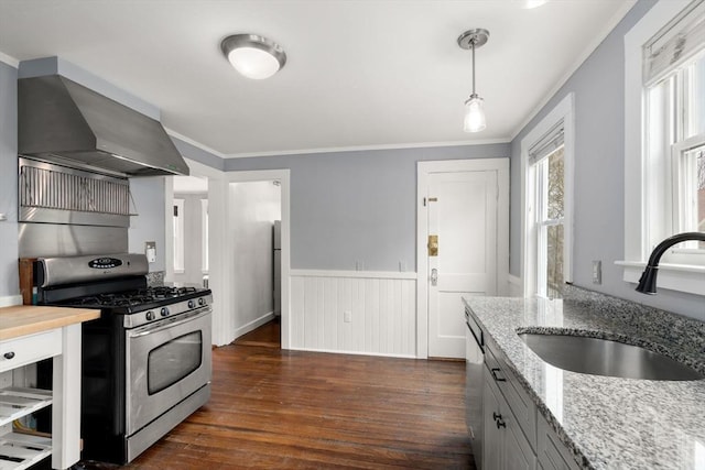 kitchen with a sink, wall chimney range hood, stainless steel range with gas stovetop, dark wood-type flooring, and crown molding
