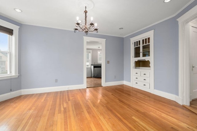 unfurnished dining area with an inviting chandelier, light wood-style floors, baseboards, and ornamental molding