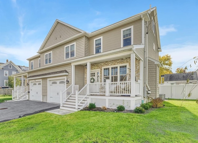 view of front of property featuring a garage, a front lawn, central air condition unit, and covered porch