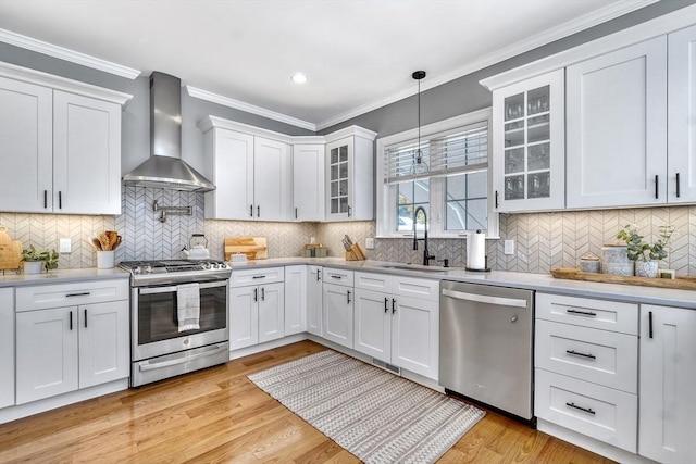 kitchen featuring white cabinetry, sink, stainless steel appliances, and wall chimney exhaust hood