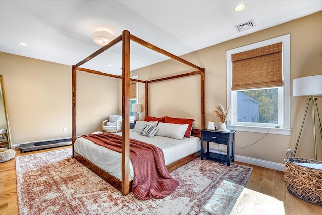 bedroom with hardwood / wood-style flooring and a baseboard heating unit