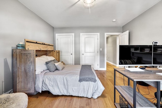 bedroom featuring light hardwood / wood-style floors and two closets