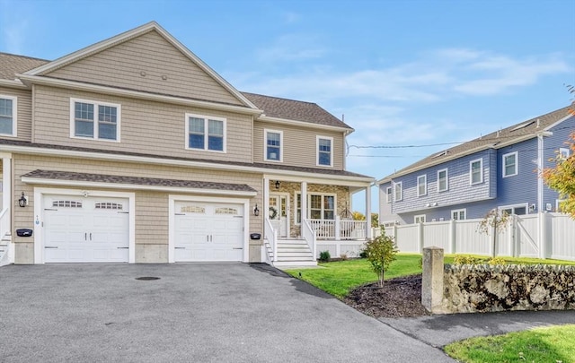 view of front of property featuring a porch, a garage, and a front lawn