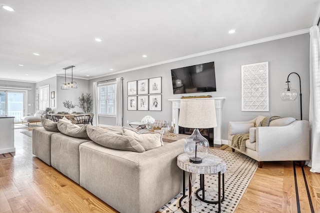 living room with crown molding, plenty of natural light, and light hardwood / wood-style flooring