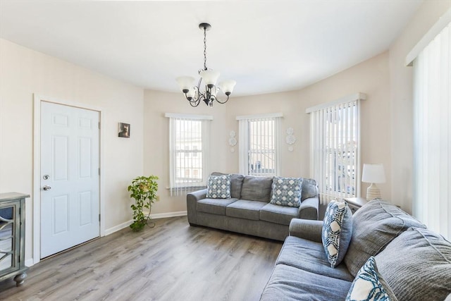 living area featuring light wood finished floors, an inviting chandelier, and baseboards